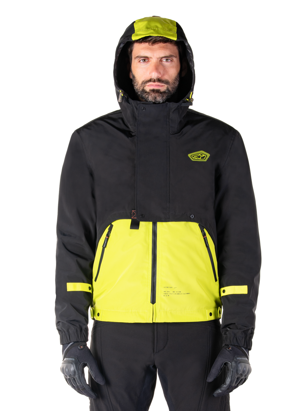 Alpinestars Mootant Waterproof Parka, Lime Punch Black motorjas, vooraanzicht, modulair 3-in-1 ontwerp met zwart bovengedeelte en fel limoengroen ondergedeelte, voorzien van een capuchon met trekkoord en logo op de borst, gedragen met zwarte broek en motorhandschoenen