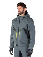 Alpinestars Morush Waterproof Parka, Urban Gray motorjas, ontwerp met capuchon en felgele ritsaccenten, zwarte zakdetails, gedragen met bijpassende grijze motorbroek en zwarte handschoenen, eigentijdse op streetwear geïnspireerde motorkleding.