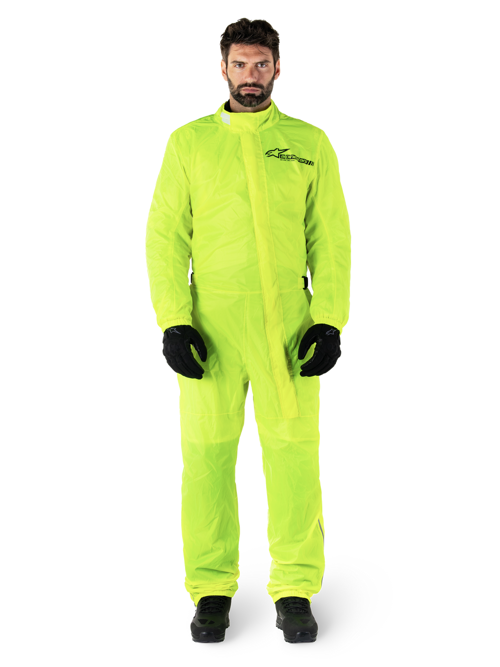 Alpinestars Hurricane Rain V2 Suit, motorregenpak, fluorgeel, mannelijk model met volledige lichaamsbescherming, zwarte handschoenen en laarzen, hoge kraag met stormflap aan de voorzijde, reflecterend logo op de borst, high-visibility waterdichte uitrusting