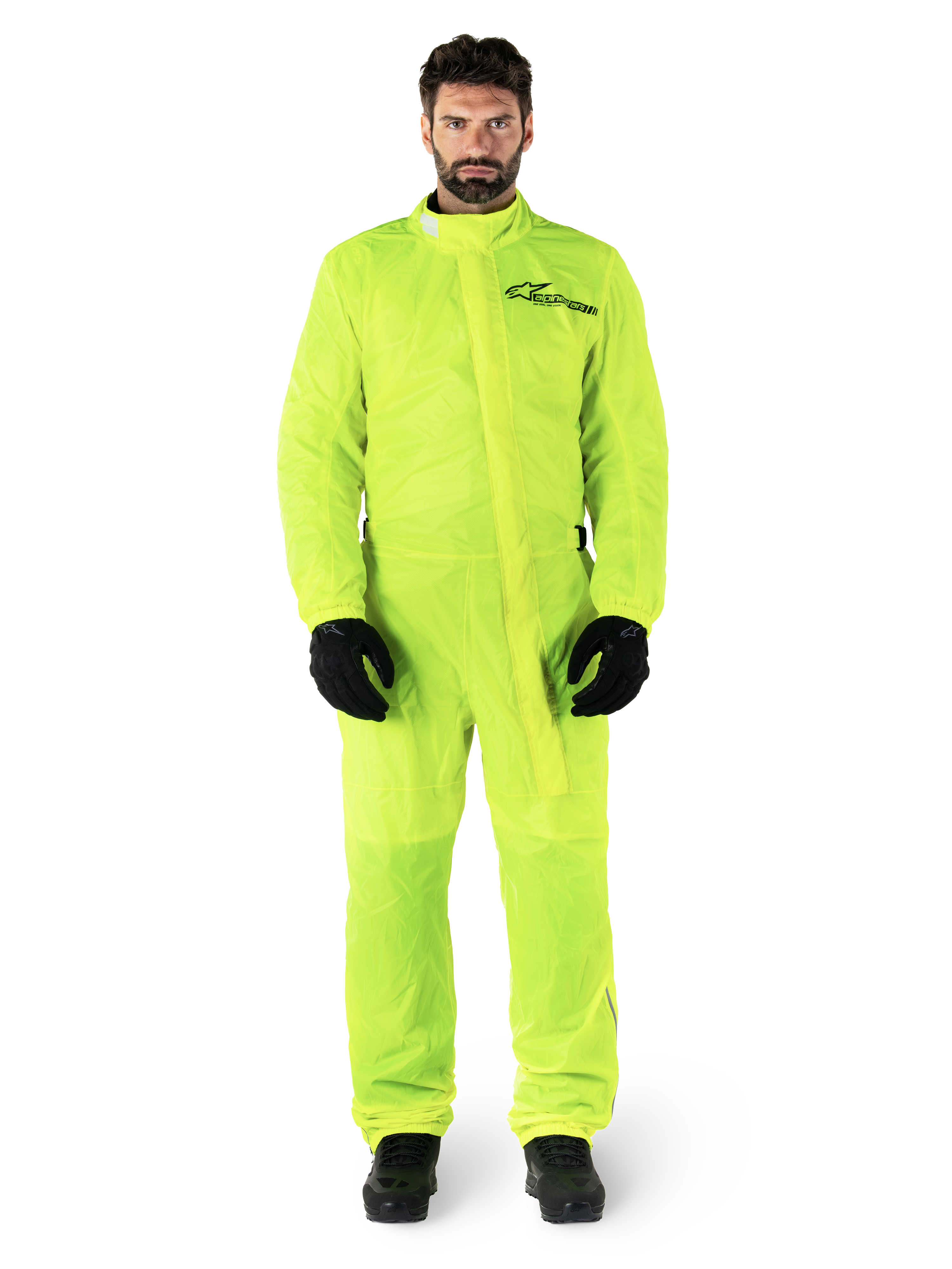 Alpinestars Hurricane Rain V2 Suit, motorregenpak, fluorgeel, mannelijk model met volledige lichaamsbescherming, zwarte handschoenen en laarzen, hoge kraag met stormflap aan de voorzijde, reflecterend logo op de borst, high-visibility waterdichte uitrusting