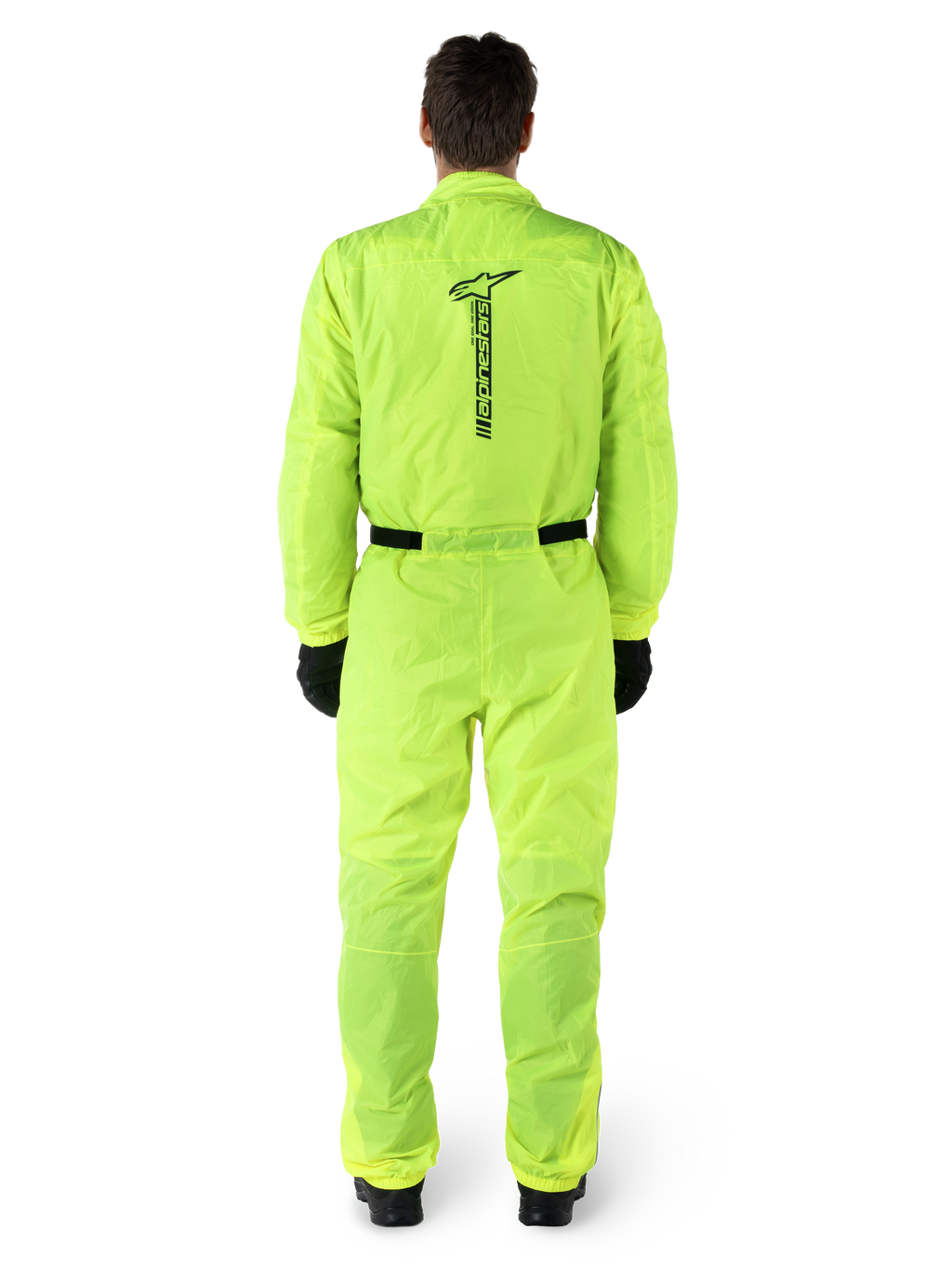 Alpinestars Hurricane Rain V2 Pak, eendelig motorregenpak, fluoriserend geel, achteraanzicht met verticale zwarte Alpinestars-branding, elastische taille en manchetten, gedragen met zwarte handschoenen en laarzen, waterdichte en windbestendige motorkleding
