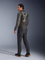 Alpinestars Axton Jacket, motorjas voor heren, zwart en antraciet, achteraanzicht met een groot grijs rondom lopend logo en accordeonpanelen op de schouders, gedragen met een donkere motorbroek en zwarte sneakers, urban contemporary stijl met race-erfgoed.