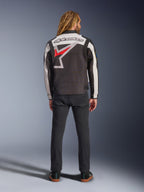 Alpinestars Axton Jacket, motorjas, zwart, off-white en felrood, achteraanzicht op een model, met een groot Alpinestars sterlogo op de rug, off-white mouwpanelen, gedragen met een zwarte broek, vintage-geïnspireerd racing teamwear ontwerp