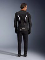 Alpinestars AST V3 Air Jacket, achteraanzicht, zwart en donkergrijs met witte accenten, groot wit Astar-logo op de achterzijde, reflecterende strepen op de rug, mesh textielconstructie, gedragen met zwarte broek en laarzen voor een sportieve rijlook