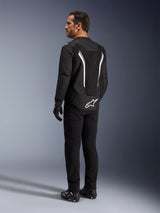 Alpinestars AST V3 Air Jacket, zwart-witte motorjas, achteraanzicht op model, voorzien van mesh-inzetstukken voor luchtstroom en wit logo op de onderrug, gedragen met zwarte technische rijuitrusting