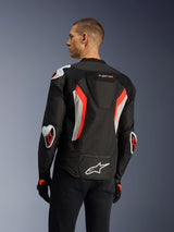 Alpinestars T-GP Air Jacket in Black Red Fluo, rear three-quarter view on a model, highlighting the aerodynamic hump, Racing GP DFS external armor on shoulders and elbows, laser-perforated mesh panels, and white and red fluo accents, sport-cut textile motorcycle jacket.