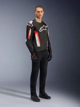 Alpinestars T-GP Air Jacket, Black Red Fluo, worn by model with black riding pants and gloves, featuring laser-perforated textile panels, white Alpinestars branding, and red accents, sport motorcycle jacket for warm weather road riding