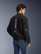Alpinestars Flight Air Jacket, zwarte motorjas, achteraanzicht met groot verticaal wit logo en mesh ventilatiepanelen, bomber-stijl met geribbelde zoom, gedragen met blauwe jeans, urban contemporary motorkleding