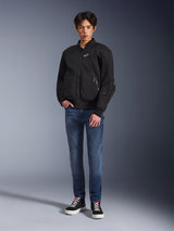 Model draagt de Alpinestars Flight Air Jacket in het zwart, een urban motorjas in bomberstijl met 3D mesh-panelen en een ritssluiting aan de voorzijde, gecombineerd met een blauwe jeans en zwarte sneakers, eigentijdse op streetstyle geïnspireerde motorkleding.