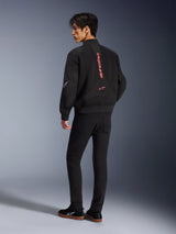 Mannelijk model draagt Alpinestars Flight Air Jacket in Black Bright Red, achteraanzicht met verticale rode branding op de rug en 3D mesh-constructie, gecombineerd met een zwarte broek en sneakers, urban motorstijl