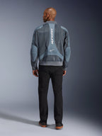 Alpinestars Flight Air Jacket in Storm Gray, achteraanzicht van een mannelijk model dat een urban-stijl motorjas draagt met 3D-meshpanelen en verticale Alpinestars-branding, gecombineerd met een zwarte broek voor een moderne forenzenlook