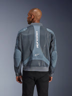 Alpinestars Flight Air Jacket in Storm Gray, achteraanzicht op een model, stedelijke motorjas voorzien van uitgebreide 3D-meshpanelen, verticale Alpinestars-branding op de rug en een geribbelde zoom en kraag in bomberstijl.