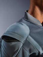 Close-up van het Alpinestars Flight Air Jacket in Storm Gray, met de nadruk op de externe schouderprotectiezak met zichtbaar honingraat-pantser, 3D mesh ventilatiepanelen en geribbelde kraag voor technisch stedelijk motorrijden