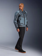 Alpinestars Flight Air Jacket, Storm Gray, op urban bomber geïnspireerde motorjas, gedragen door een mannelijk model met zwarte broek en sneakers, voorzien van uitgebreide 3D-mesh ventilatiepanelen en externe protectorzakken, moderne streetwear beschermende kleding voor rijden bij warm weer