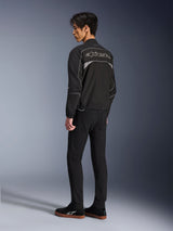 Alpinestars Unite Jacket, Urban Motorcycle Jacket, Black and Dark Gray, back view showing large outlined Alpinestars logo, reflective piping and panels, minimalist softshell design, worn with black pants and casual footwear