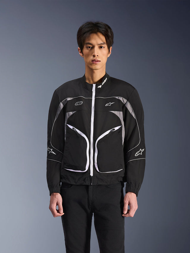 Alpinestars Unite Jacket, minimalist urban motorcycle jacket, Black and Dark Gray with white accents, features a white front zipper, reflective piping, and Alpinestars branding on the chest and sleeves, contemporary streetwear style for riders.
