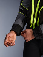 Alpinestars Unite Jacket, urban motorjas, zwart en asfaltgrijs met neongele accenten, close-up van handen die de elastische mouwmanchet aanpassen, minimalistische op streetwear geïnspireerde beschermende kleding