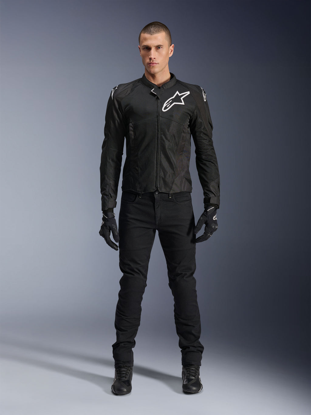 Alpinestars Viper Air V4 Jas, zwarte textiele motorjas, wit logo op de borst en schouders, gedragen met zwarte motorbroek en handschoenen, voorzien van tech mesh panelen voor luchtstroom, volledige studio-opname