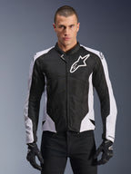 Alpinestars Viper Air V4 motorjas, sportieve motorjas, zwart en wit, gedragen door een rijder, tech mesh- en textielconstructie met witte schouderpanelen, opvallend sterlogo op de borst, sport-performance ontwerp, gecombineerd met zwarte motorhandschoenen