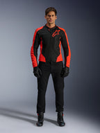 Mannelijk model draagt de Alpinestars Viper Air V4-jas in Red Fluo en Black, gecombineerd met een zwarte motorbroek, handschoenen en laarzen, voorzien van ademende mesh-panelen voor ventilatie en een opvallend sterlogo op de borst, sportieve motorkleding voor op de weg