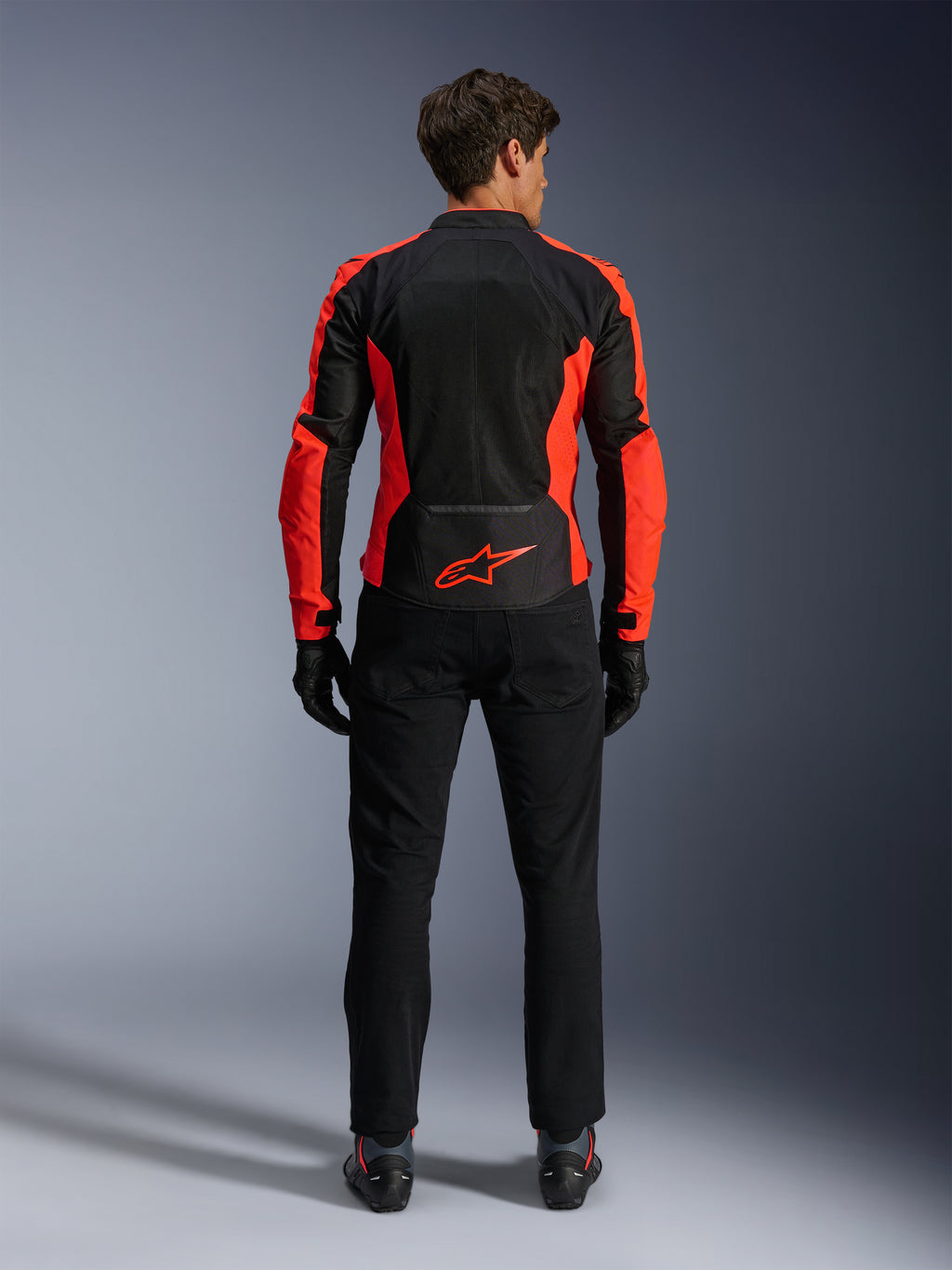 Alpinestars Viper Air V4 Jas, fluorrood en zwart, achteraanzicht met grote tech mesh-panelen en felrode fluorescerende accenten aan de zijkanten, rood Alpinestars-logo op de onderrug, gedragen met zwarte motorbroek en handschoenen