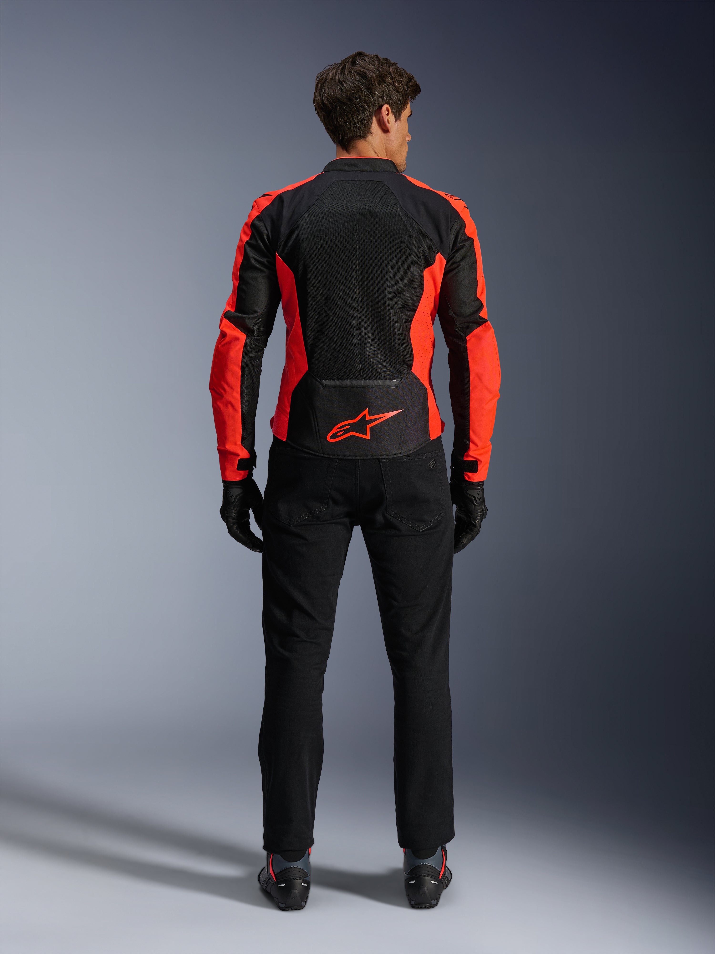 Alpinestars Viper Air V4 Jas, fluorrood en zwart, achteraanzicht met grote tech mesh-panelen en felrode fluorescerende accenten aan de zijkanten, rood Alpinestars-logo op de onderrug, gedragen met zwarte motorbroek en handschoenen