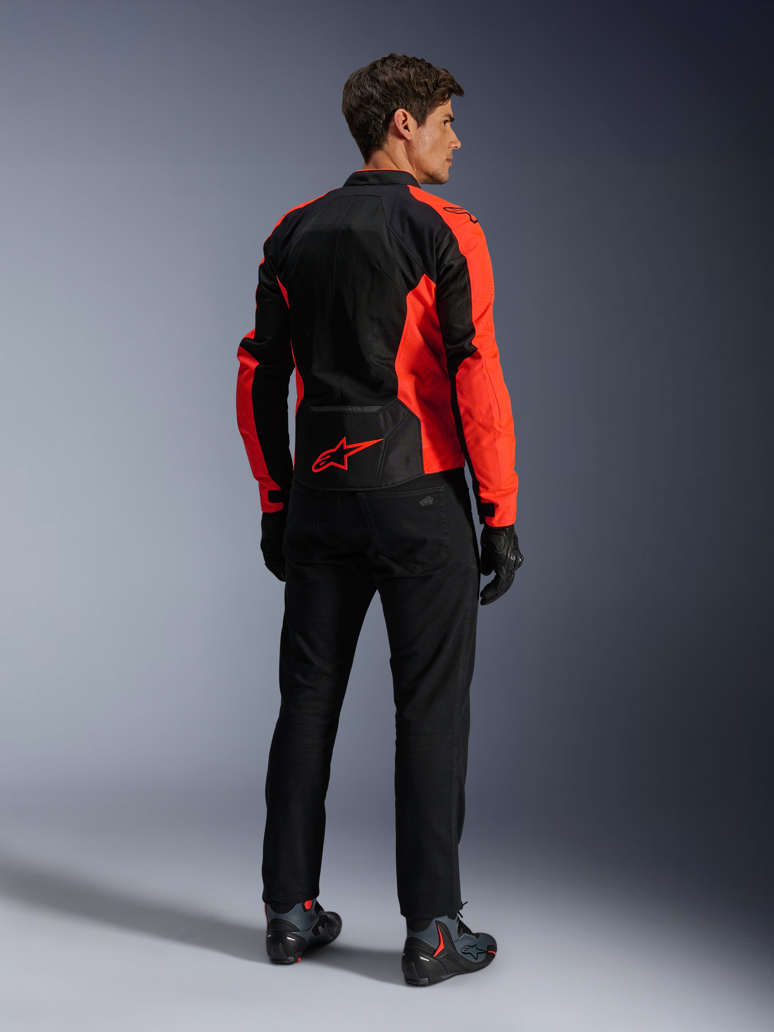 Alpinestars Viper Air V4 Jas, Red Fluo Black, achteraanzicht op model, voorzien van technische mesh-panelen en een rood sterlogo op de onderrug, gecombineerd met een zwarte motorbroek en handschoenen voor een complete motorlook.