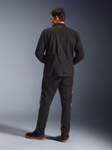 Achteraanzicht van de Alpinestars Dice Jacket in het zwart, urban motorjas in veldjasstijl met geplooide schouders en tailleverstellers, gecombineerd met een zwarte en beige motorbroek en sneakers, eigentijdse stijl voor stedelijk woon-werkverkeer