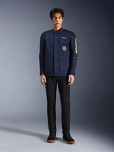Alpinestars Dice Jacket, urban motorjas, donkerblauw en zwart, gedragen door een model met zwarte broek en zwarte schoenen, modern veldjas-ontwerp met meerdere zakken, verticale borstritssluiting en witte Alpinestars-branding op de mouwen.