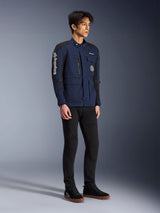 Alpinestars Dice Jacket, donkerblauw en zwart, moderne motorjas in veldstijl gedragen door een model met zwarte broek en zwarte hoge sneakers, met meerdere utility-zakken, verticale Alpinestars-branding op de mouw en geweven patches, urban eigentijdse motorkleding