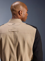 Alpinestars Dice Jacket, stedelijke motorjas, beige en zwart, close-up detail van de achterkant van de kraag en schouder, voorzien van een geborduurd logo, robuuste polykatoen twill constructie, street-ready werkkledingstijl