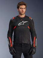 Alpinestars T-Sps Air V2 motorjas, zwart en fluorood motorjack, groot wit Astars-logo op de borst, gestructureerde tech mesh-constructie voor een optimale luchtstroom, gedragen door model met zwarte motorhandschoenen, sportieve snit met rode accenten op de schouders en mouwen