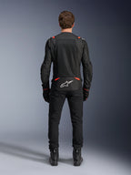 Alpinestars T-SPS Air v2 Jas in zwart en rood fluo, achteraanzicht met grote mesh ventilatiepanelen en wit Alpinestars-logo op de onderrug, gedragen met zwarte motorbroek en laarzen