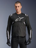 Alpinestars T-SPS Air V2 motorjas, textiele motorjas, zwart met witte accenten, groot wit logo op de borst, geperforeerd mesh-ontwerp voor ventilatie, gedragen met een zwarte broek en handschoenen