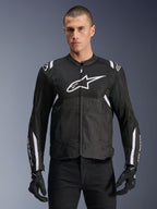 Alpinestars T-SPS Air V2 motorjas, textiele motorjas, zwart met witte accenten, groot wit logo op de borst, geperforeerd mesh-ontwerp voor ventilatie, gedragen met een zwarte broek en handschoenen