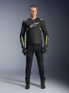 Alpinestars T-Sps Air V2 Jas, Zwart en Geel Fluo, textiele motorjas met mesh-panelen, gedragen door mannelijk model met zwarte broek en handschoenen, voorzien van wit Alpinestars-logo op de borst, urban sport motorkleding