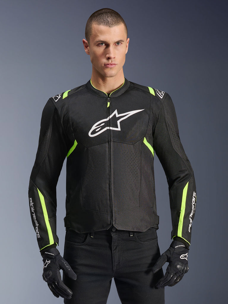 Alpinestars T-Sps Air V2 Jas in Black Yellow Fluo, mannelijk model met de geventileerde textieljas met mesh-panelen en wit logo op de borst, gecombineerd met zwarte motorhandschoenen, urban motorkleding
