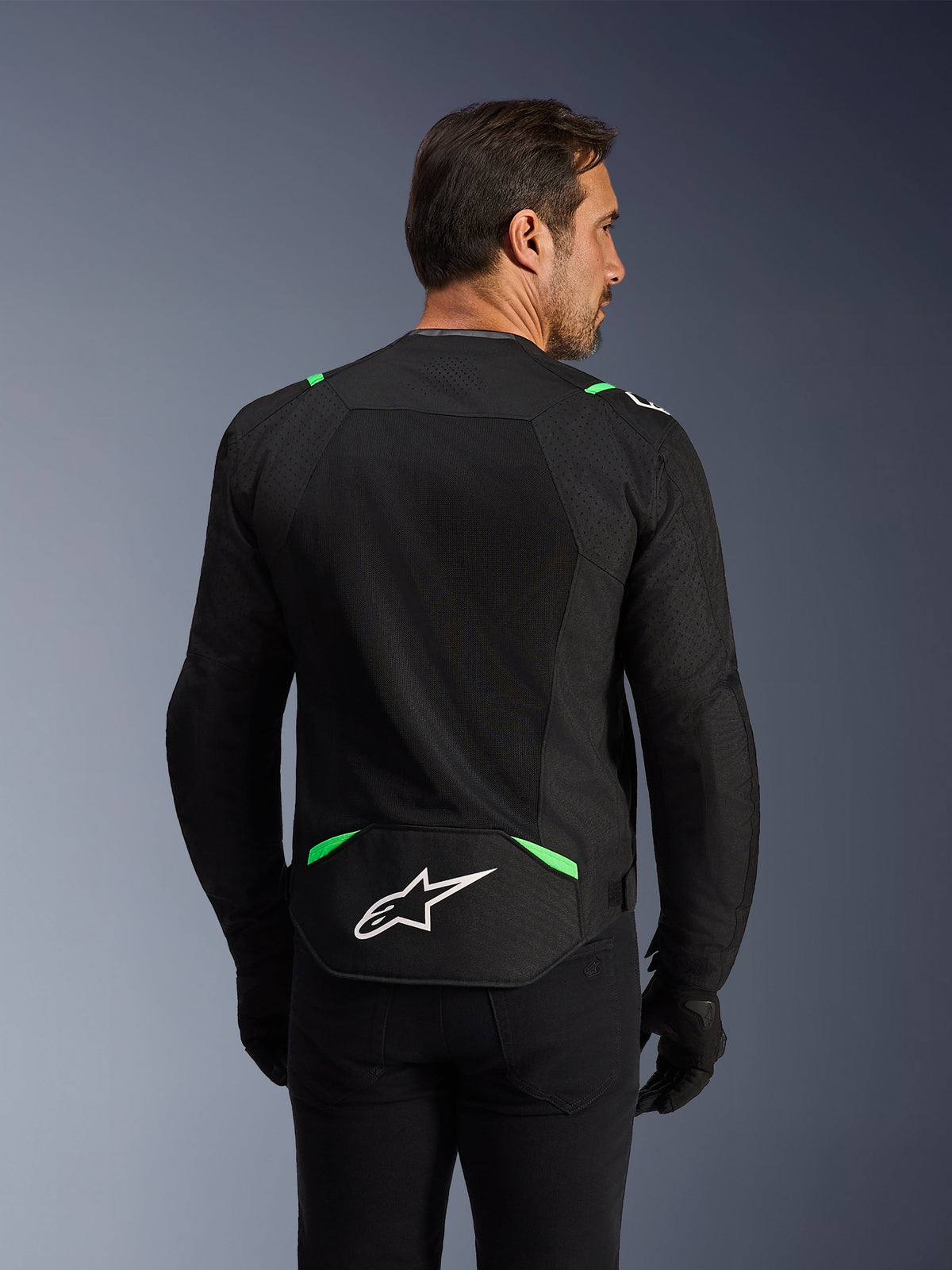 Alpinestars T-SPS Air V2 Jas, textiele motorjas, zwart met fluogroen, achteraanzicht met grote tech mesh-panelen voor ventilatie, wit Alpinestars-logo op de onderrug, sportieve ergonomische pasvorm voor stadsritten