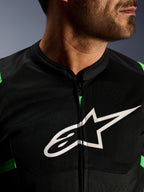 Close-up van Alpinestars T-SPS Air V2 Jacket, zwart en fluo groen, voorzien van ademende tech mesh panelen, centrale ritssluiting en een prominent wit Alpinestars sterlogo op de borst, performance motorkleding