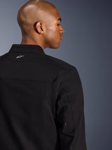 Alpinestars Bruiser Jacket, textiele urban motorjas, zwart, close-up achteraanzicht met een geborduurd goudkleurig logo op de bovenrug, metalen oogjes op de mouwen en geplooide schouderpanelen voor verbeterde bewegingsvrijheid.