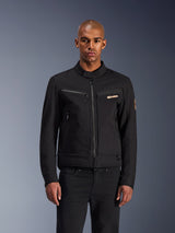Alpinestars Bruiser Jacket, zwarte urban motorjas, vooraanzicht op een model, klassieke werkkleding-esthetiek, borstzakken met ritssluiting, kraag met knoopsluiting en Alpinestars-logo, ontworpen voor stadsmotorrijders