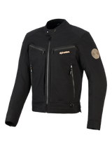 Alpinestars Bruiser Jas, zwarte urban motorjas, voorzien van borst- en steekzakken met rits, goudkleurige branding en Oscar-spiraalpatch op de schouder, op werkkleding geïnspireerd textielontwerp.