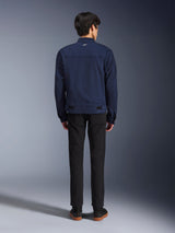 Alpinestars Bruiser Jacket in Dark Blue, back view on model, textile motorcycle jacket with a workwear-inspired design, featuring a small white logo on the back collar and adjustable waist tabs, paired with black pants