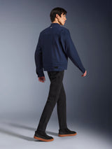 Alpinestars Bruiser Jacket in Dark Blue, urban textile motorcycle jacket, rear view on model walking, paired with black pants and gum-soled sneakers, featuring workwear-inspired design and adjustable waist tabs