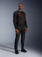 Alpinestars Troop-Air Pro Jas in Black Red Fluo, technische gepantserde mesh motorjas gedragen door een mannelijk model met bijpassende zwarte gepantserde broek en hoge motorlaarzen, volledige studio-opname.