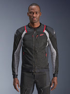 Alpinestars Troop-Air Pro Jacket, zwart, asgrijs en felrood, gedragen door een model, motorjas van mesh met geperforeerde ventilatiepanelen, voorzien van rode zakken met rits en witte logo's op de schouders, technische motoruitrusting met protectie