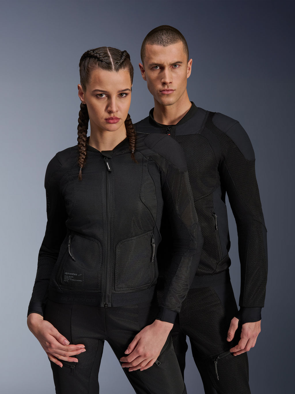 Man en vrouw in Alpinestars Troop-Air en Stella Troop-Air jassen, zwarte technische mesh motorjassen, voorzien van 2D tech mesh-structuur voor ventilatie en versterkte panelen, eigentijdse urban motorkleding