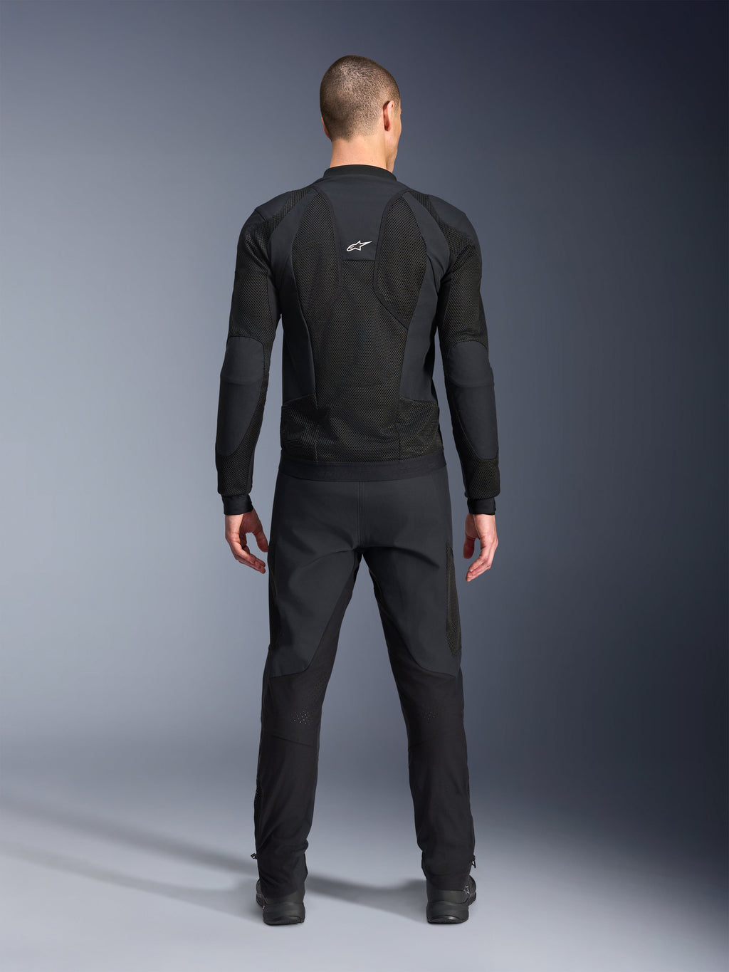 Alpinestars Troop-Air Pro Jacket, achteraanzicht, zwart, technische motorjas met grote mesh ventilatiepanelen en een wit Alpinestars-logo, gecombineerd met een zwarte broek, urban contemporary rijkleding