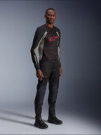 Alpinestars Troop-Air Jas, technische mesh motorjas in zwart, asgrijs en helderrood, gedragen door een model met bijpassende zwarte broek en laarzen, met een rood Alpinestars-logo op de borst, urban contemporary motorkleding