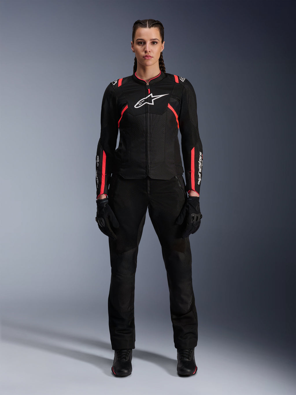 Alpinestars Stella T-SPS Air v2 Jas, motorjas voor dames, zwart met Diva Pink, vooraanzicht, wit logo op de borst, mesh ventilatiepanelen, gedragen met zwarte broek en handschoenen, strakke urban motoruitrusting